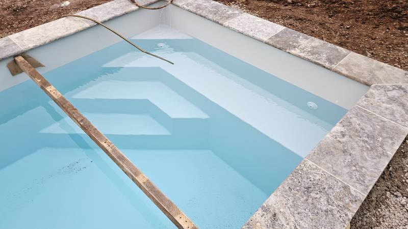 Installation d'une piscine en coque polyester moins de 10 mètres carrés couleur gris avec margelles en travertin Silver sur la commune de Saint Maximin la Sainte Baume